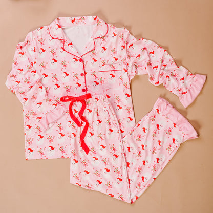The Darling Effect's Holly Jolly Santa Sweet Dreams Pajama Pants Set, featuring festive prints and ultra-soft fabric, is shown on a light beige background.