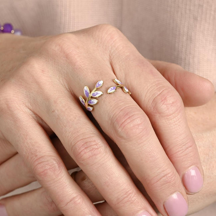 Close-up of a hand wearing a delicate ring with leaf design on a beige background