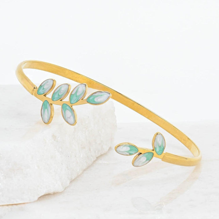 Gold bracelet with green enamel leaves on a white background