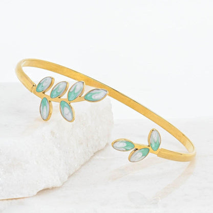 Gold bracelet with green enamel leaves on a white background