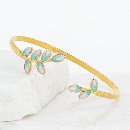 Gold bracelet with green enamel leaves on a white background
