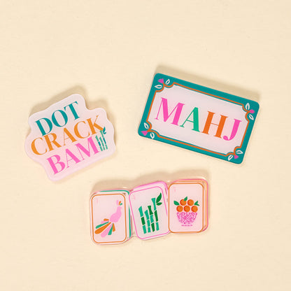 The Darling Effect's Let's Play Mahjong Little Magnet Set features four playful acrylic magnets inspired by Mahjong tiles, each with phrases like DOT CRACK BAM and MAHJ, plus charming tile illustrations, arranged on a beige surface.