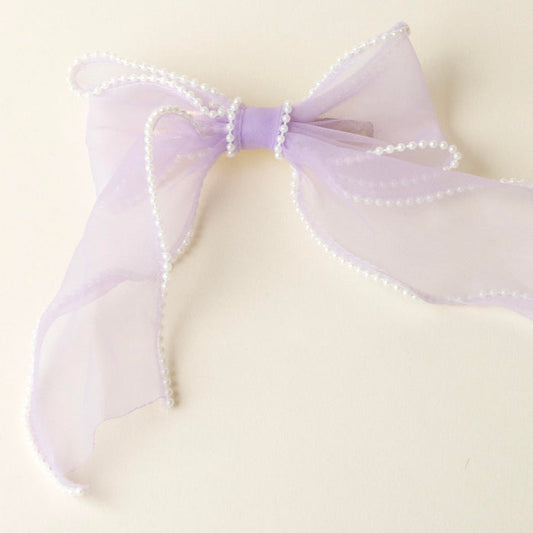 The Lilac Sheer Pearl Hair Bow by the-darling-effect features a light purple, sheer ribbon bow with white pearl-like beads along the edges, styled on a plain, light background.