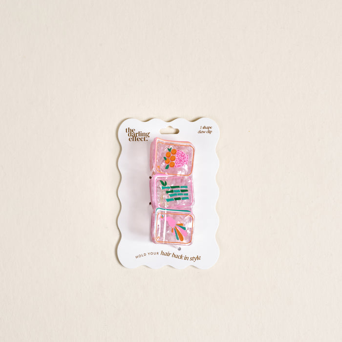 The Darling Effect Mahjong Tiles Shape Up Claw Clip set features three pink, translucent clips with colorful floral designs on a scalloped white card—ideal for adding charm to any cute hairstyle.