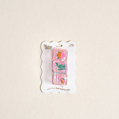 The Darling Effect Mahjong Tiles Shape Up Claw Clip set features three pink, translucent clips with colorful floral designs on a scalloped white card—ideal for adding charm to any cute hairstyle.