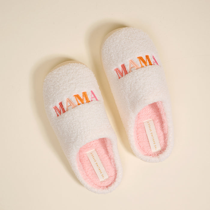 The Darling Effect's Mama Fuzzy Slippers feature soft white exteriors, pink interiors, and colorful "MAMA" embroidery on top—perfectly cozy and stylish for home comfort.