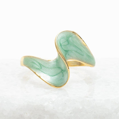 Green ceramic ring with gold rim on a textured white surface