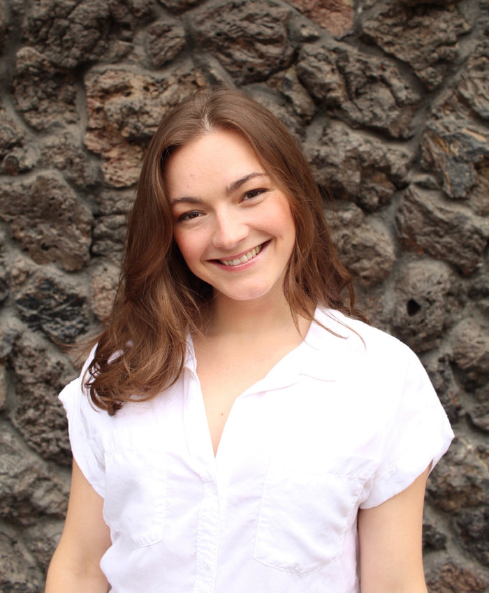 Woman in a white shirt standing against a stone wall
