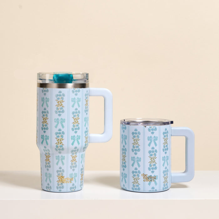 Two light blue mugs with matching vertical floral and bow designs and white handles sit side by side. One is the-darling-effect's Oh So Fancy Blue 20 oz Lifestyle Flip Straw Tumbler, featuring a clear lid for insulated sipping.
