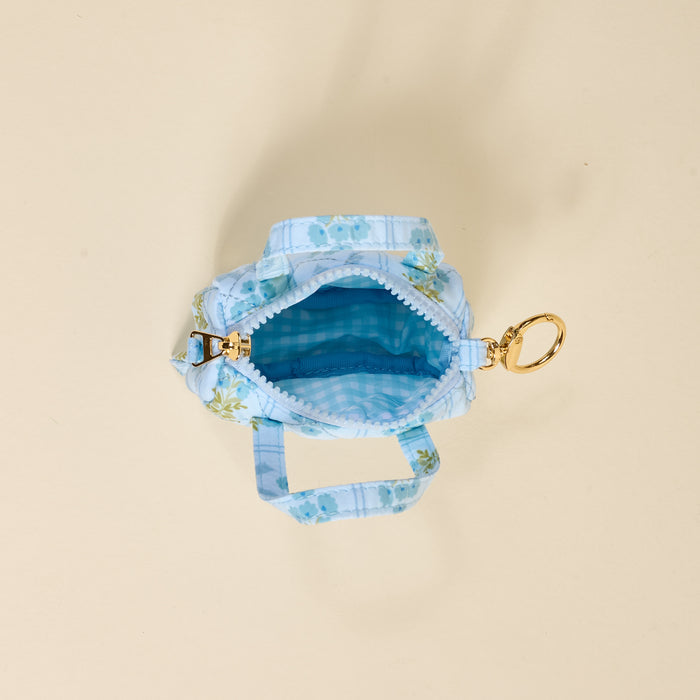 The Darling Effect’s Oh So Fancy Blue Itty Bitty Duffle Bag Charm features a light blue quilted floral pattern, gingham lining, gold zipper, and clip—perfect as a unique bag accessory or quilted charm.