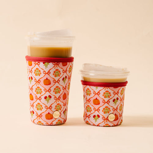 Sip your favorite drinks in style with The Darling Effect's Patchwork Pumpkins Sip Savvy Drink Sleeves, featuring pink neoprene sleeves adorned with pumpkins, orange bows, and florals—a charming seasonal accessory.
