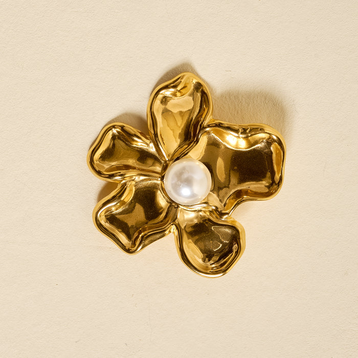 The Darling Effect’s Pearl Core Flower Timeless Brooch features wavy gold petals and a central white pearl, creating a vintage-inspired accessory beautifully set against a light beige background.
