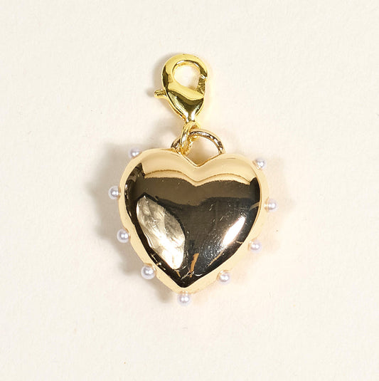 The Darling Effect’s Pearl Lined Heart Jewelry Charm Gold features a gold heart shape, small white pearls along the edge, and a lobster clasp—perfect for charm jewelry or your own charm bar. Photographed on a light beige background.