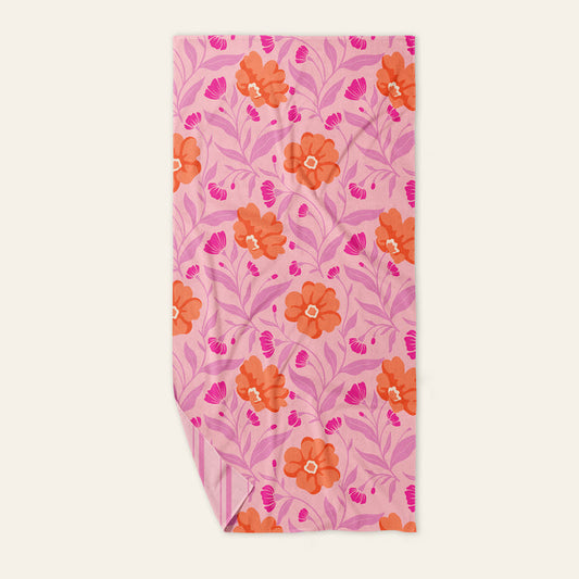 The Darling Effect Poppin' Petals Hot Pink XL Quick-Dry Beach Towel features an orange and pink floral pattern with leaf designs and a striped underside, combining vibrant style and fast-drying comfort for sunny beach days.