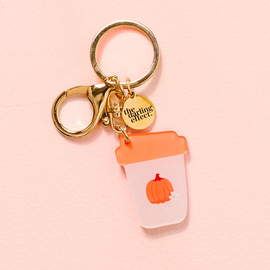 The Darling Effect’s Pumpkin Spice Latte Acrylic Keychain features a gold clip, engraved round charm, and an acrylic to-go cup charm with an orange lid and pumpkin illustration—perfect for anyone who loves cute, unique keychains.
