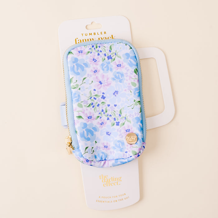The Secret Garden Blue Tumbler Fanny Pack by the-darling-effect features a stylish blue and purple floral design, gold zippers, and water-resistant material—perfect for carrying your essentials on the go. Comes in white packaging.