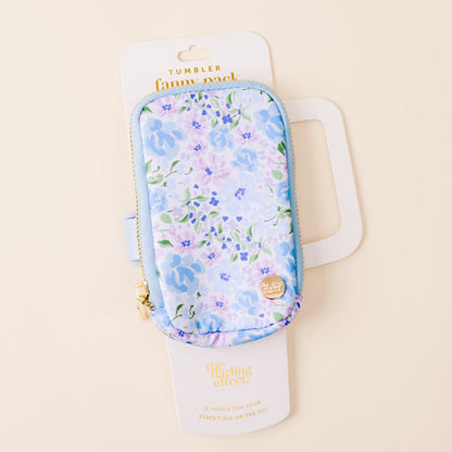 The Secret Garden Blue Tumbler Fanny Pack by the-darling-effect features a stylish blue and purple floral design, gold zippers, and water-resistant material—perfect for carrying your essentials on the go. Comes in white packaging.