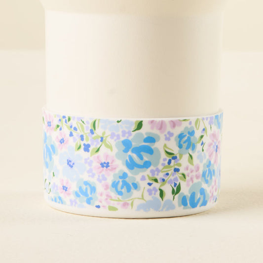 The-darling-effect's Secret Garden Blue Tumbler Silicone Boot features a pastel floral pattern with blue, purple, and pink flowers on white, plus a silicone boot for tumbler protection against dents.