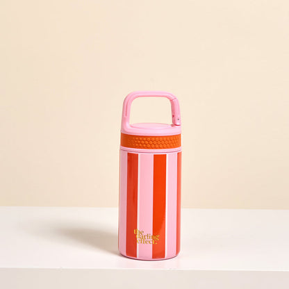 The Darling Effect’s Sicily Stripes Pink 6 oz Lil’ Bitty Bottle features red and pink stripes, a pink handle, and a yellow logo—your ideal travel hydration companion that pops on any white surface with a beige backdrop.