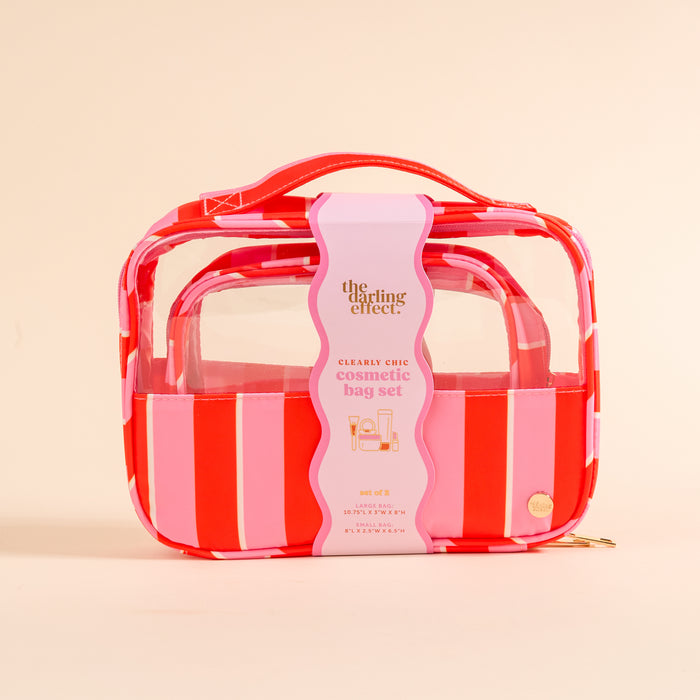 The Darling Effect Sicily Stripes Pink Clearly Chic Cosmetic Bag Set features a transparent design with bold red and pink stripes, a gold zipper, carrying handle, and product details on the label.