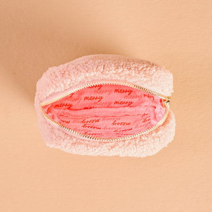 The Darling Effect's Square Holiday Gift Bow Red Teddy Pouch is a small, fluffy pouch with a pink interior featuring "merry" in red script—perfect as a festive organizer for the holidays.