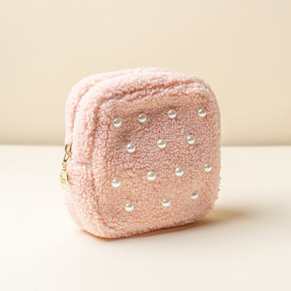 The Darling Effect's Square Pearl Blush Teddy Pouch features light pink sherpa, front faux pearls, and a gold zipper with a round charm, shown against a neutral background.