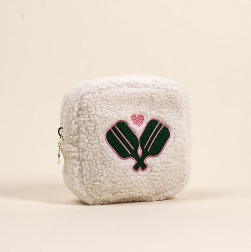 The-darling-effect's Square Pickleball Paddles Teddy Pouch is a small, white sherpa zip pouch featuring two green pickleball paddles crossed with a pink heart embroidered above them.