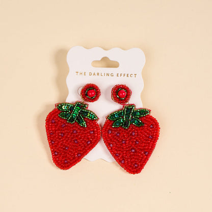 Strawberry Beaded Earrings by The Darling Effect feature green sequin leaves on a pale yellow background—a playful, vibrant addition to your beaded jewelry collection.