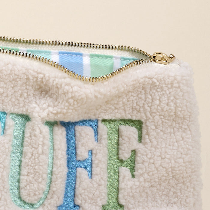 The Darling Effect's Stuff Edit Teddy Pouch features cream sherpa fabric with “STUFF” in bold blue and green embroidery, a gold zipper, and a cozy blue, green, and white plaid-lined interior—perfect for your accessories.