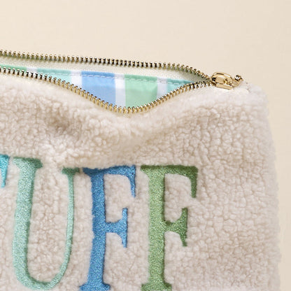 The Darling Effect's Stuff Edit Teddy Pouch features cream sherpa fabric with “STUFF” in bold blue and green embroidery, a gold zipper, and a cozy blue, green, and white plaid-lined interior—perfect for your accessories.