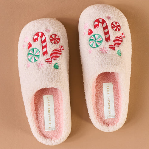 The Darling Effect’s Sugar Rush Fuzzy Slippers are light pink with a plush, fuzzy texture and embroidered candy canes and sweets on top—holiday-ready comfort labeled on the insole.