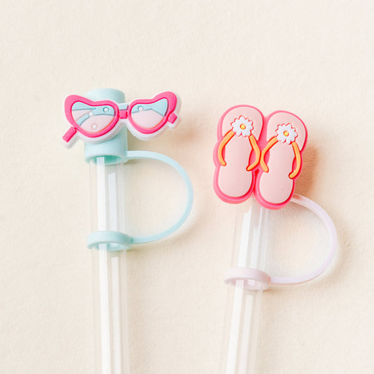 The-darling-effect’s Sunny Style Straw Topper Set includes two reusable clear plastic straws with colorful silicone toppers—pink heart-shaped sunglasses and pink flip-flops with white flowers—and comes with silicone bands to attach the charms.