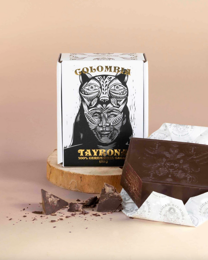 Chocolate bar with a packaging box featuring a stylized face design on a beige background
