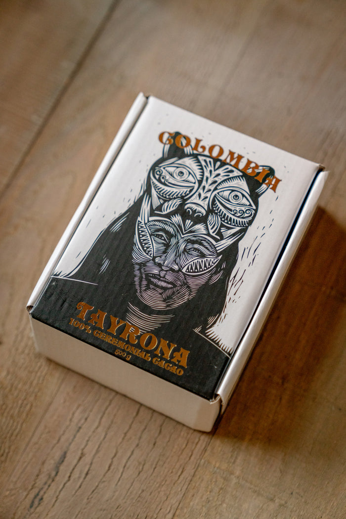 Cigar box with a design of a face with tattoos and the word 'Colombia' on a wooden surface