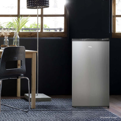 TCL 18 in. 3.1 Cu. Ft. Compact Single Door Mini Fridge in Silver (TRM31S4AV) in a modern room with a dining table and chairs.