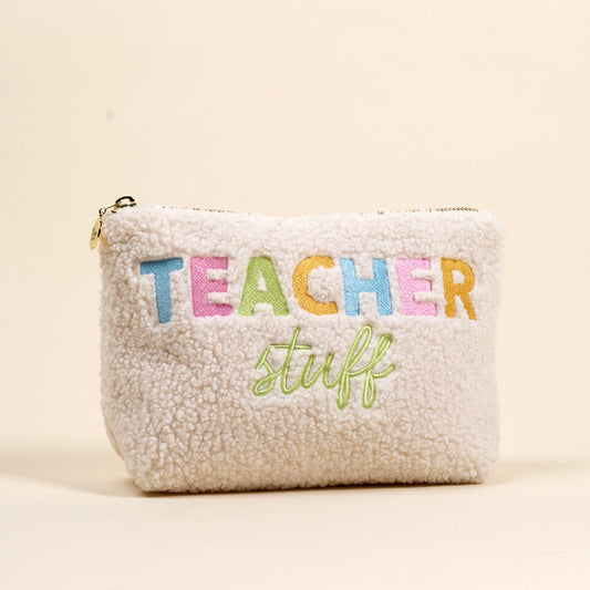 The-darling-effect’s Teacher Stuff Teddy Pouch is a white sherpa pouch with colorful “TEACHER” letters and green script “stuff” on the front, shown on a plain beige background.
