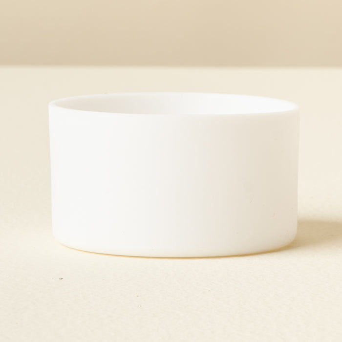 The Darling Effect White Tumbler Silicone Boot is shown on a light, cream surface with a neutral background, offering added protection for your tumbler.