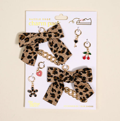 The Darling Effect's Wild & Free Dazzle Shoe Charm Pack features two leopard-print bows with gold chains and five sneaker charms—a key, cherries, pink heart, black flower, and gold hoop—displayed on a white card.